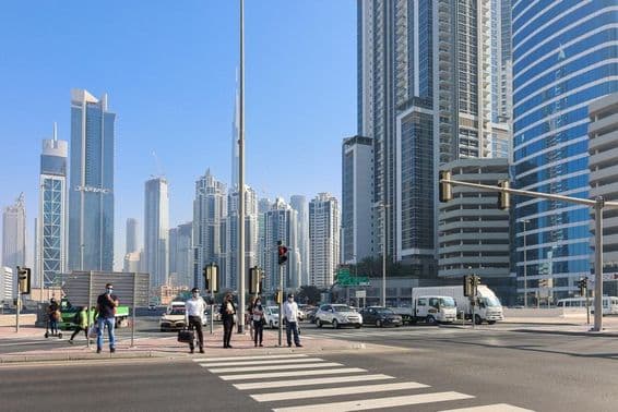 People walking at a pedestrian crossing in Dubai's business district.