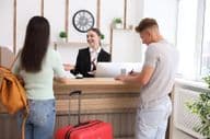 Smiling receptionist in uniform with a hotel key card.