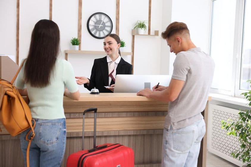 Smiling receptionist in uniform with a hotel key card.