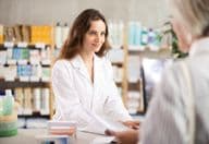 A woman selling medications at a pharmacy for the management of chronic illnesses.