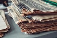 Old newspapers stacked with cobwebs.