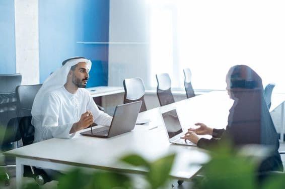 Man and woman in traditional attire working in a Dubai business office.