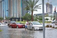 People pushing cars out of water in flooded streets of Dubai.