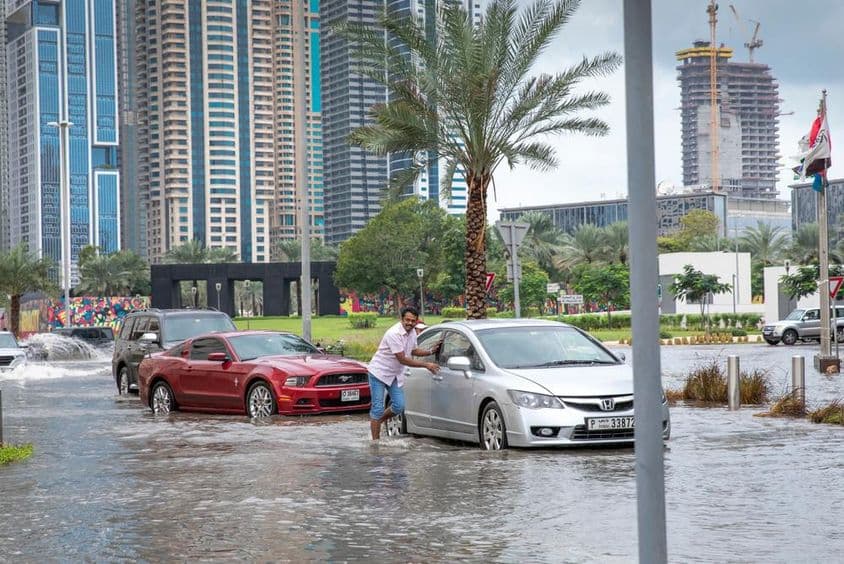 People pushing cars out of water in flooded streets of Dubai.