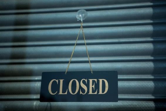 Closed sign on black background, placed on metal shutter.