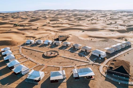 Camp in the desert surrounded by vast sand dunes.