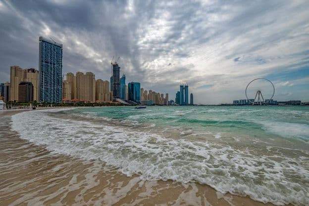 Bad weather in Dubai with rain, strong winds, and waves by the shore.