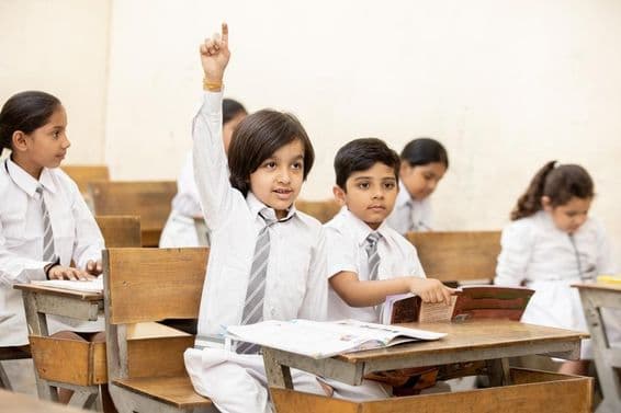 Happy Indian schoolboy raises hand to answer a question.