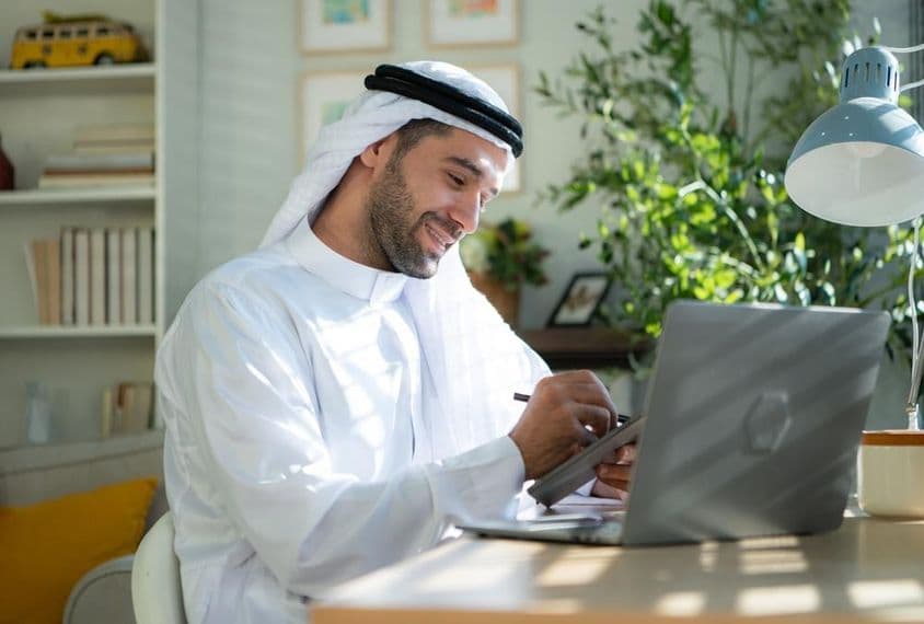 Young Arab businessman working from home on laptop.