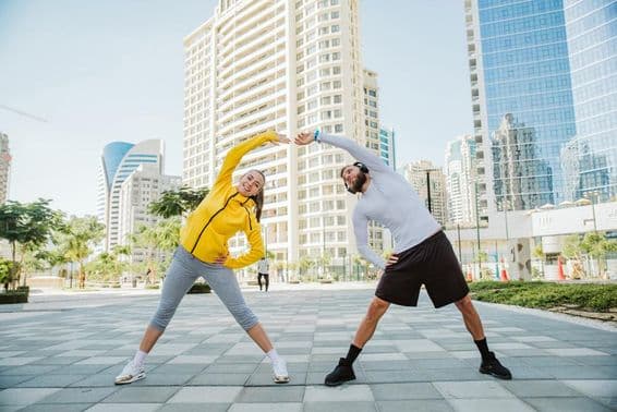 A man and a woman stretching together after a workout in Dubai.