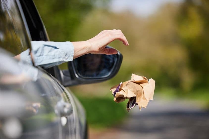 Driver drops litter from window onto highway.