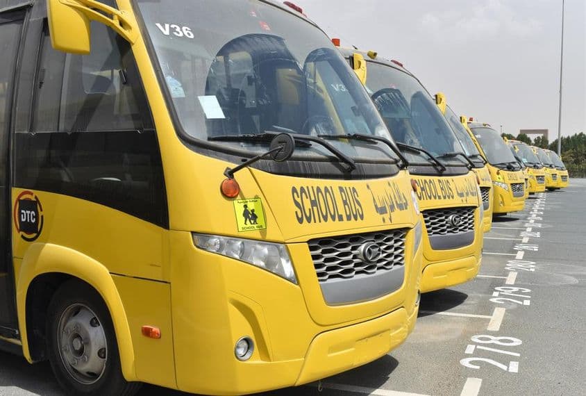 Several yellow school buses lined up in a parking lot in Dubai.