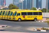 Line of yellow Dubai school buses parked outside.