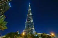 Burj Khalifa tower lit up at night, viewed from below.