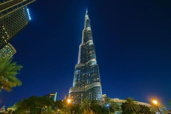 Burj Khalifa tower lit up at night, viewed from below.