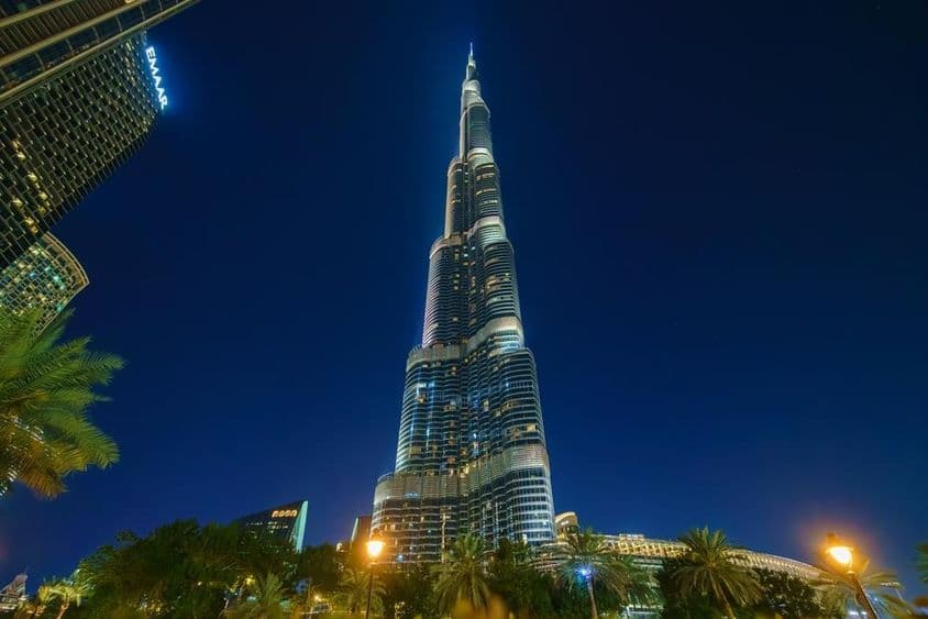 Burj Khalifa tower lit up at night, viewed from below.