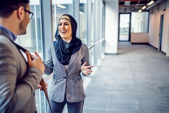 Smiling attractive Arab woman discussing a building with a real estate agent.