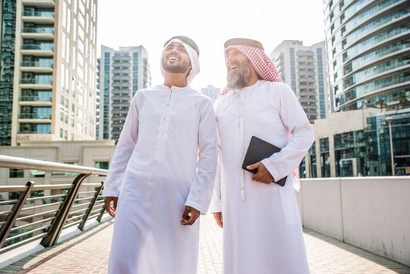 Two businessmen in traditional Emirati attire meeting in Dubai.