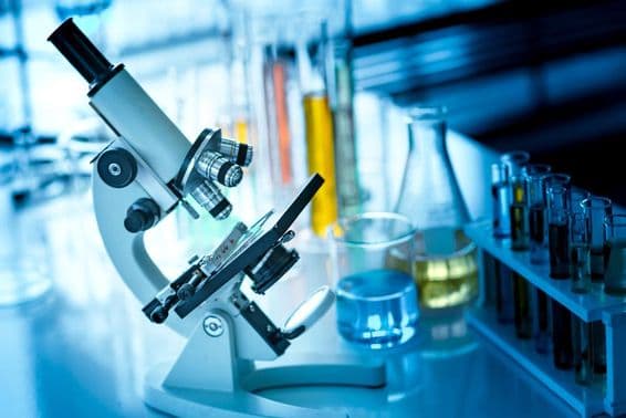 Microscope on a table with chemical tubes and glassware.