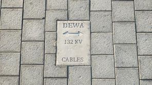 Sign warning of cables on stone-tiled floor in Dubai.