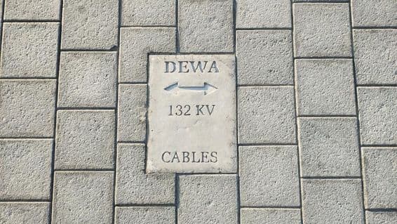Sign warning of cables on stone-tiled floor in Dubai.