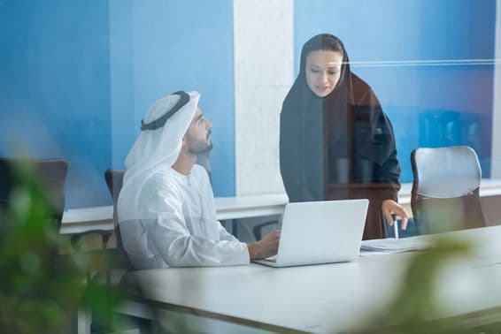 Man and woman in traditional clothing working in a Dubai business office.