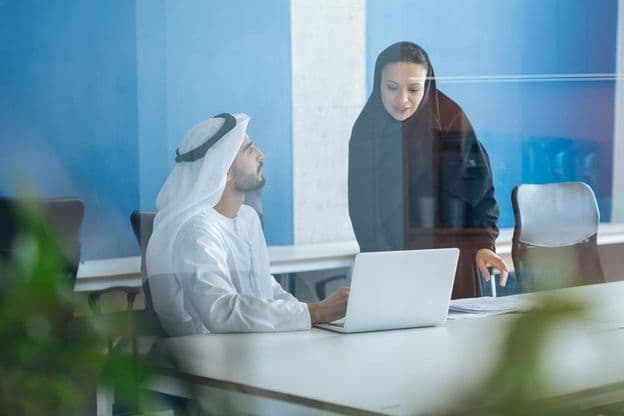 Man and woman in traditional clothing working in a Dubai business office.