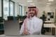 Smiling Saudi Arabian man in traditional attire working.
