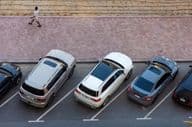 Overhead view of parked cars in Dubai and a man walking on a paved sidewalk.