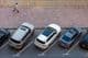 Overhead view of parked cars in Dubai and a man walking on a paved sidewalk.