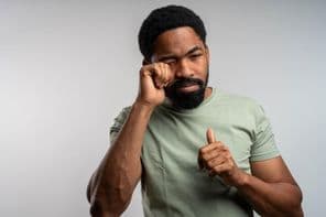 A person rubbing their eyes uncomfortably, feeling irritated and tired.