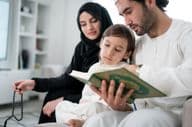 Young parents reading the Koran to their son during Ramadan.