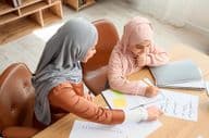 A young Muslim girl being taught Arabic by her mother.