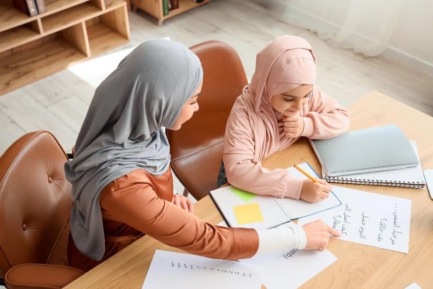 A young Muslim girl being taught Arabic by her mother.