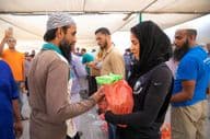 Volunteers distribute food packages to workers during the Iftar meal.