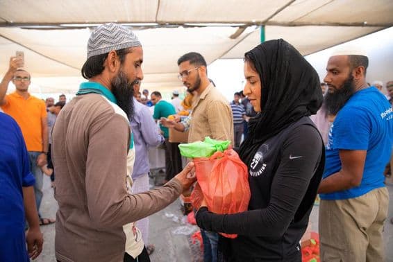 Volunteers distribute food packages to workers during the Iftar meal.