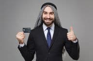Smiling Arabic Muslim businessman with a credit card.