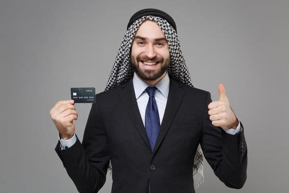 Smiling Arabic Muslim businessman with a credit card.