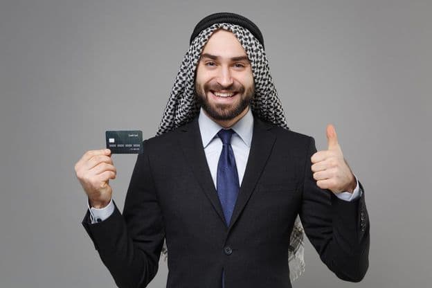 Smiling Arabic Muslim businessman with a credit card.