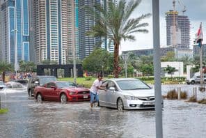 People pushing cars out of water on flooded streets in Dubai.