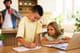 Siblings doing homework at home using laptop.