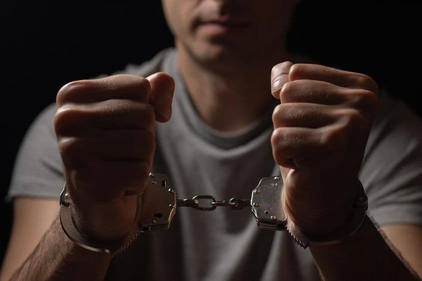 Hands held in front with handcuffs.