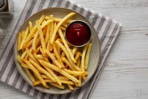 Homemade fries and ketchup on a plate.