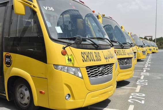 Several yellow school buses lined up in a parking lot in Dubai.