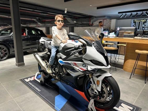 Boy with sunglasses sitting on a BMW motorcycle.
