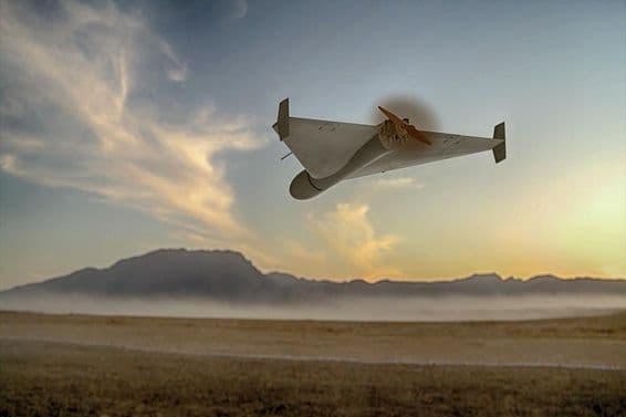 A military kamikaze drone flying over desert mountains.