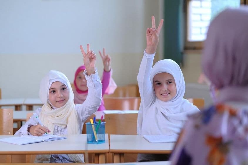 Muslim school students raising their hands.