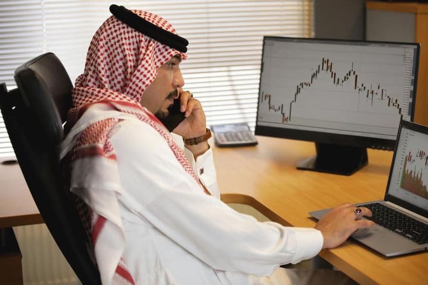 Arab man working on a laptop in the office, looking at stock market