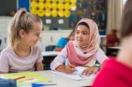 Muslim schoolgirl sits near a classmate during a lesson.