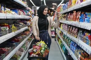 A young Arab woman looks at snacks in a supermarket.